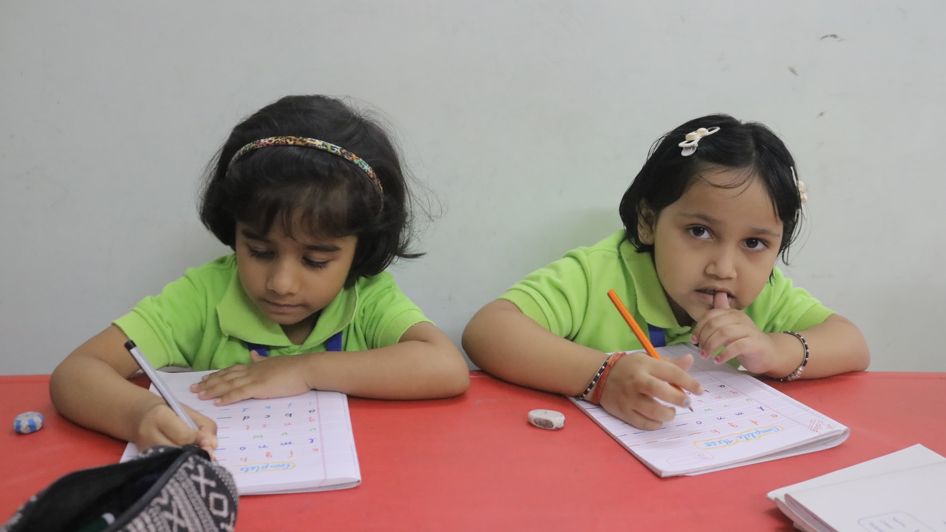 Little Buds students practising handwriting at a classroom table