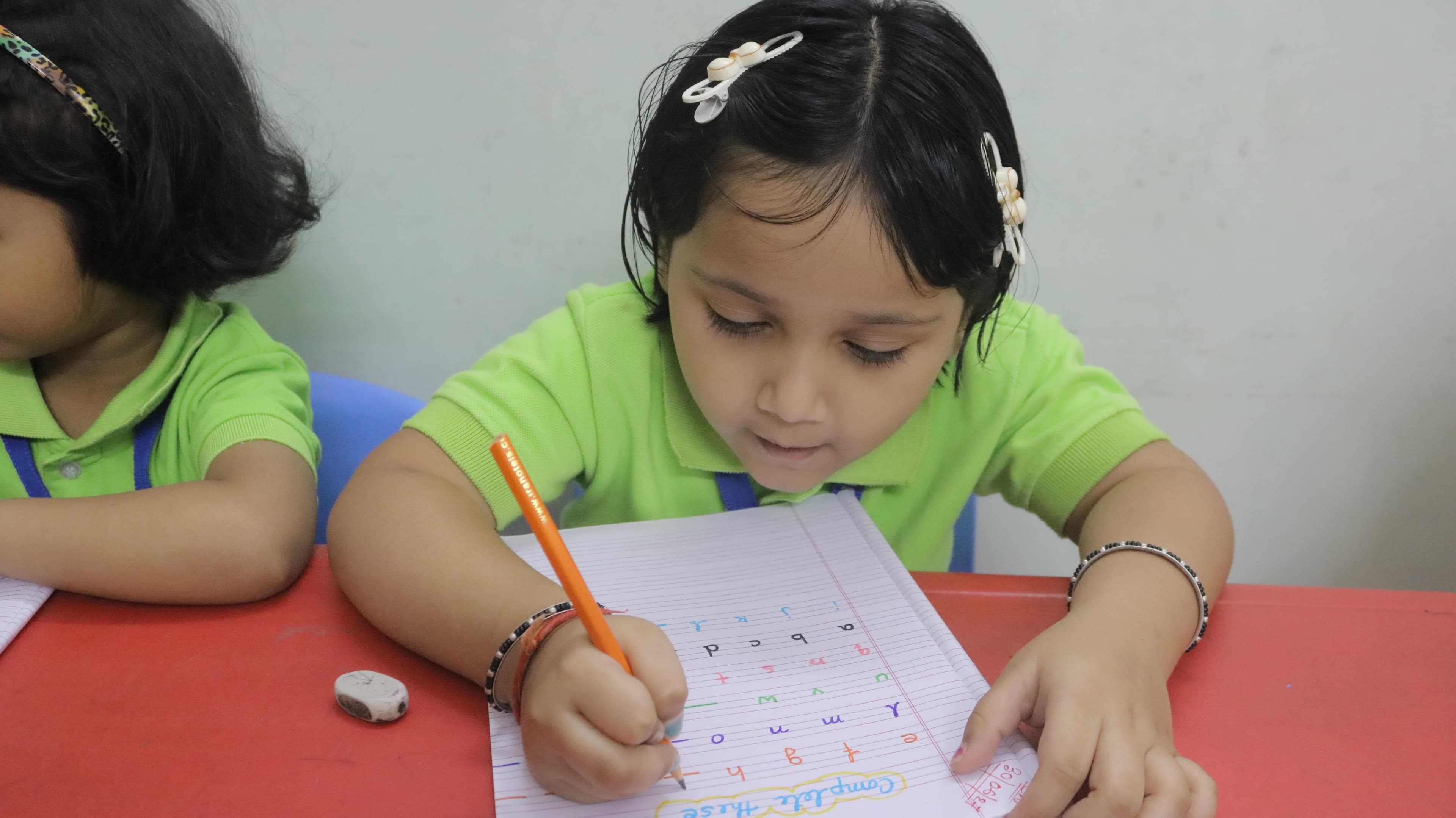 Student concentrating on a writing exercise at Little Buds