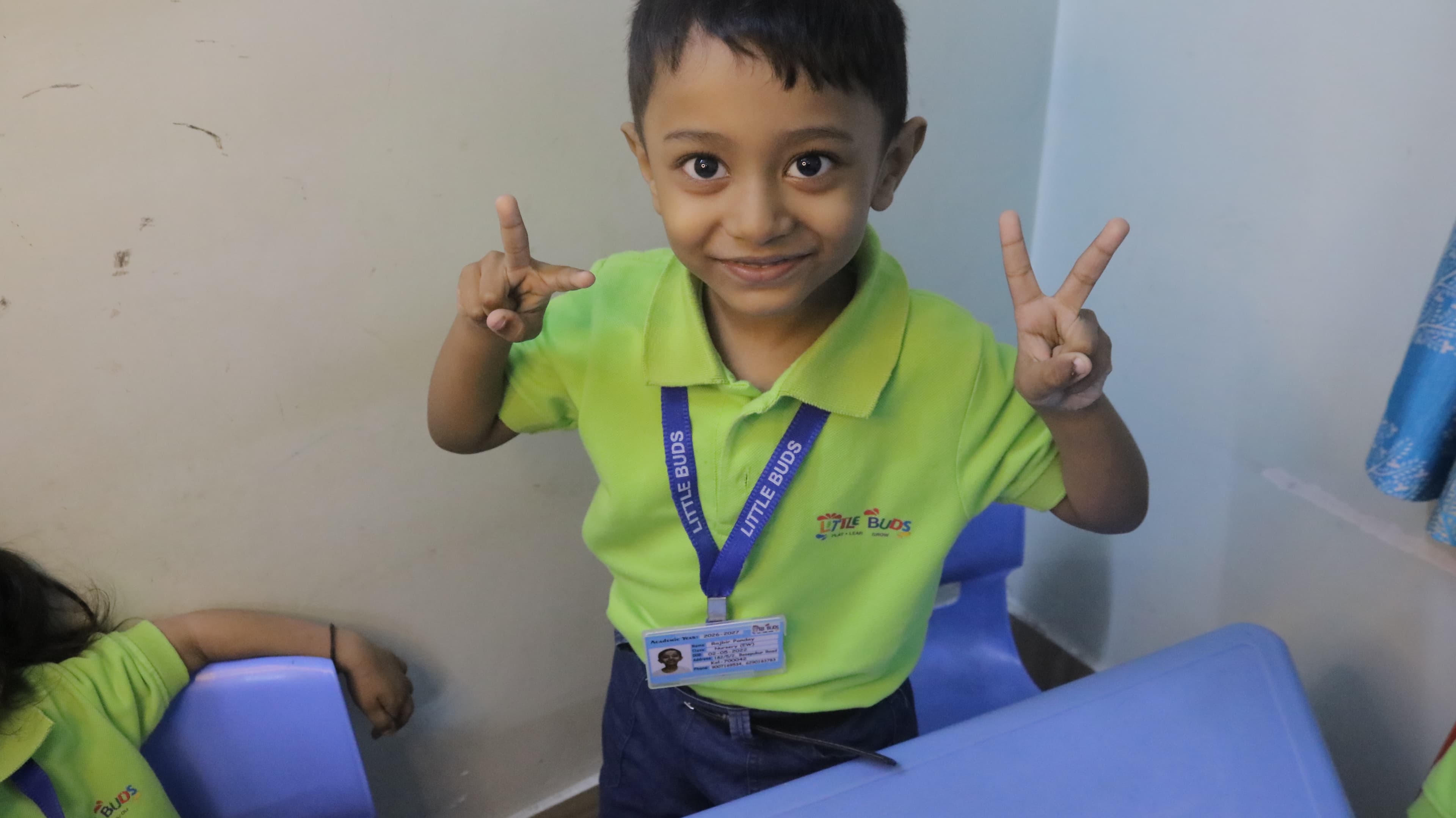 Little Buds student giving a peace sign with a big smile