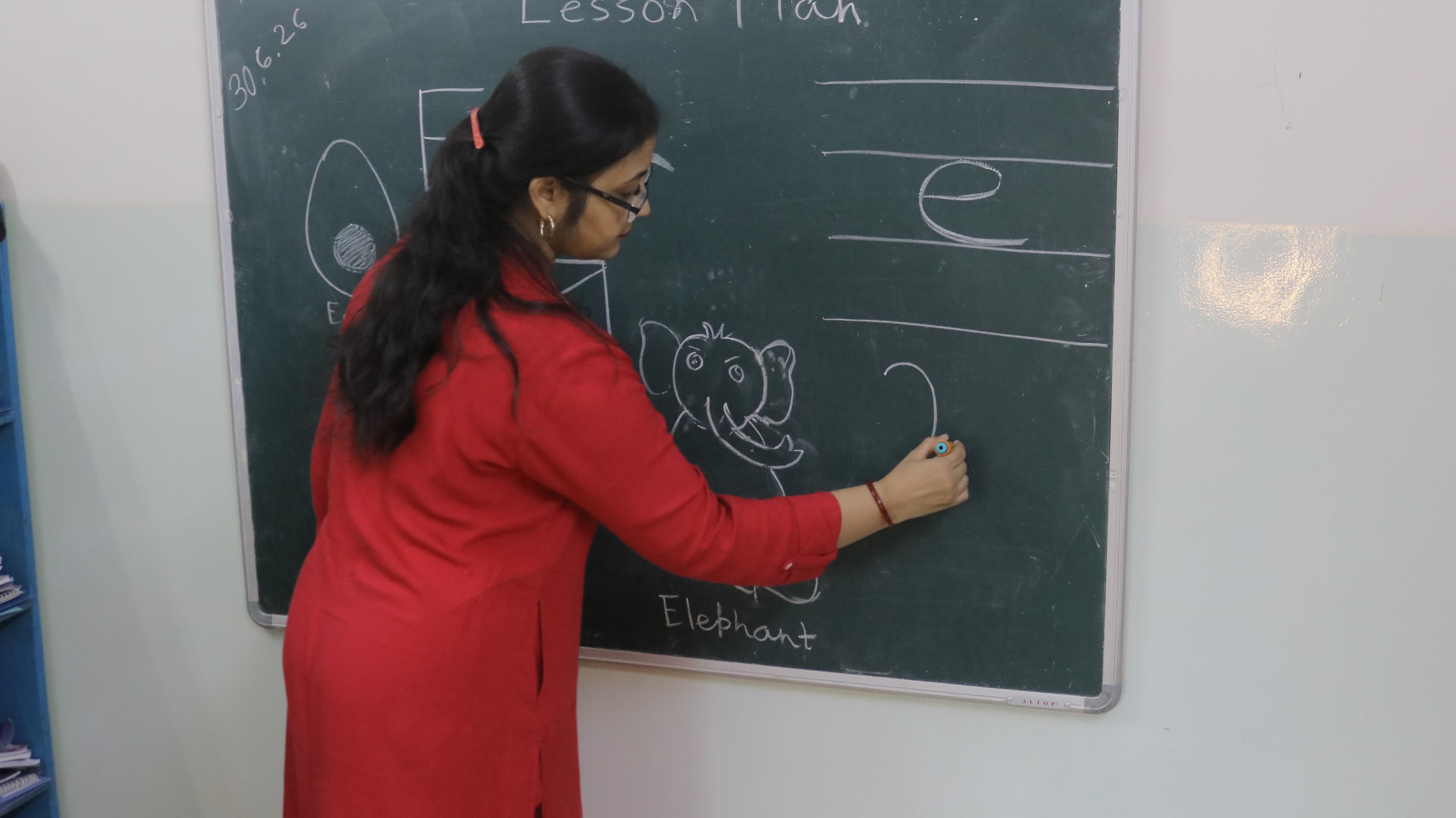 Teacher writing a lesson on the chalkboard at Little Buds
