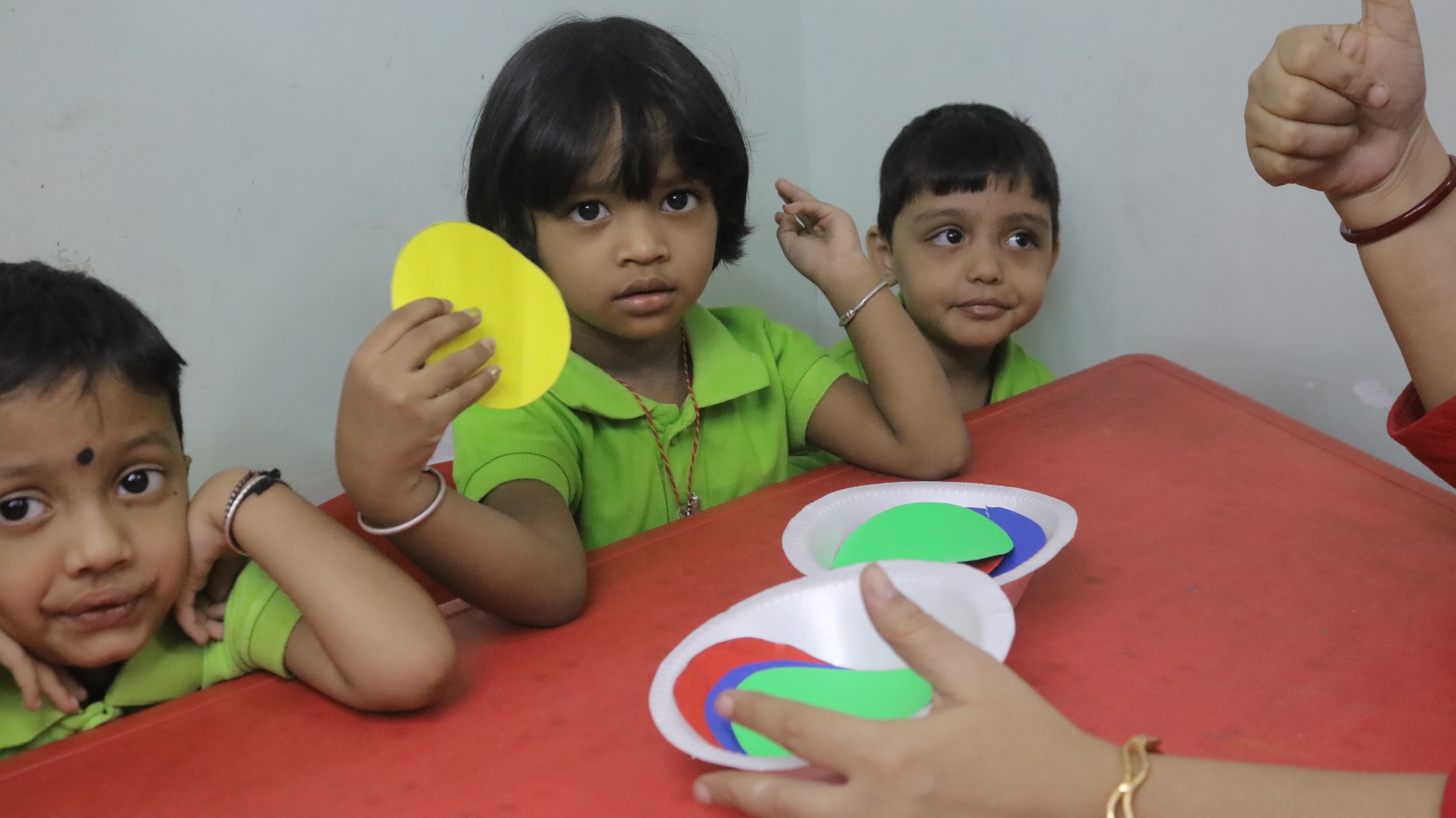 Nursery children at a table practising colour and shape matching with paper circles